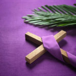 a religious cross and palm leaves on purple background.