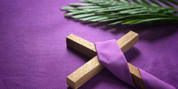a religious cross and palm leaves on purple background.